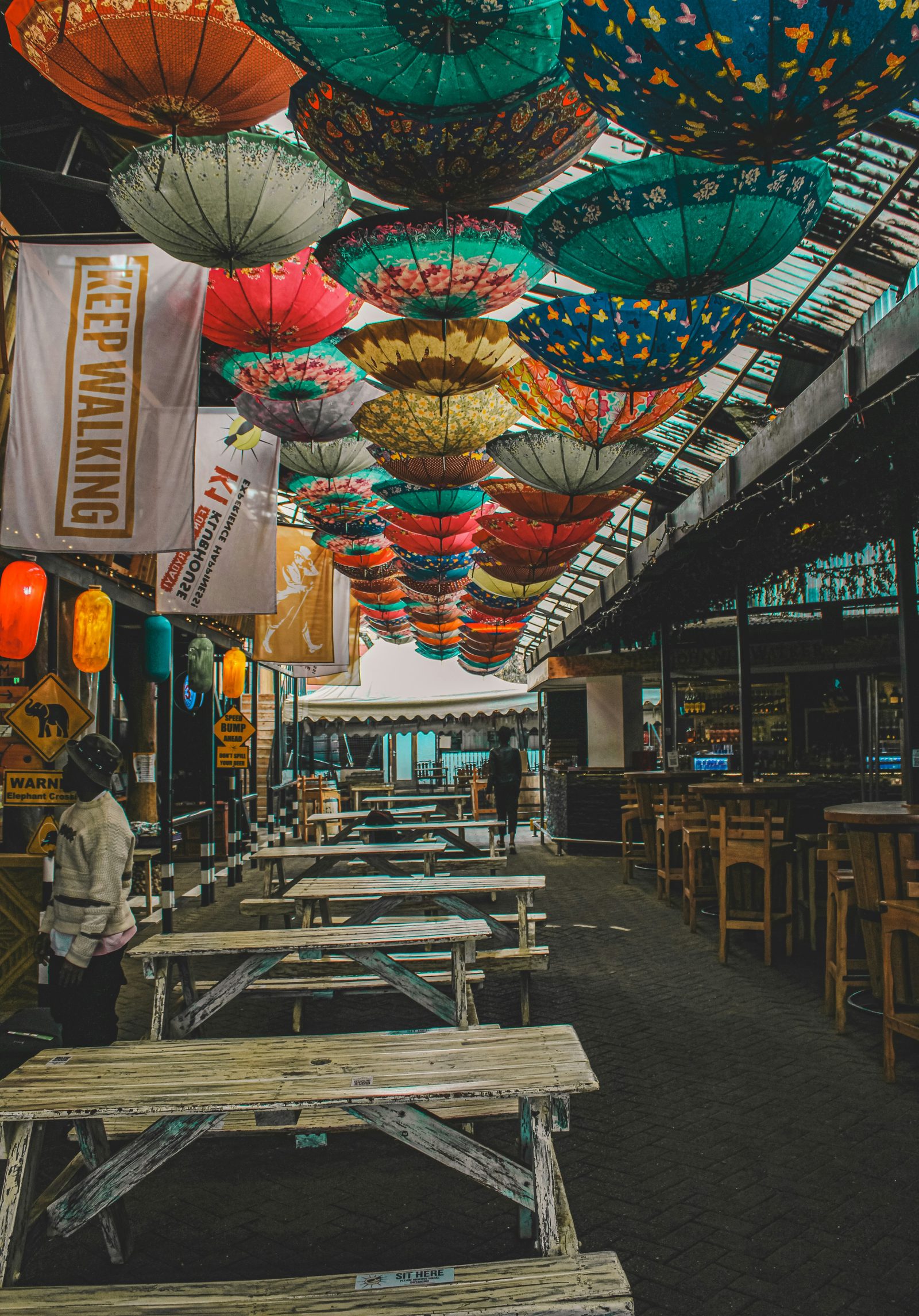 Colourful umbrellas suspended over a covered walkway with seating