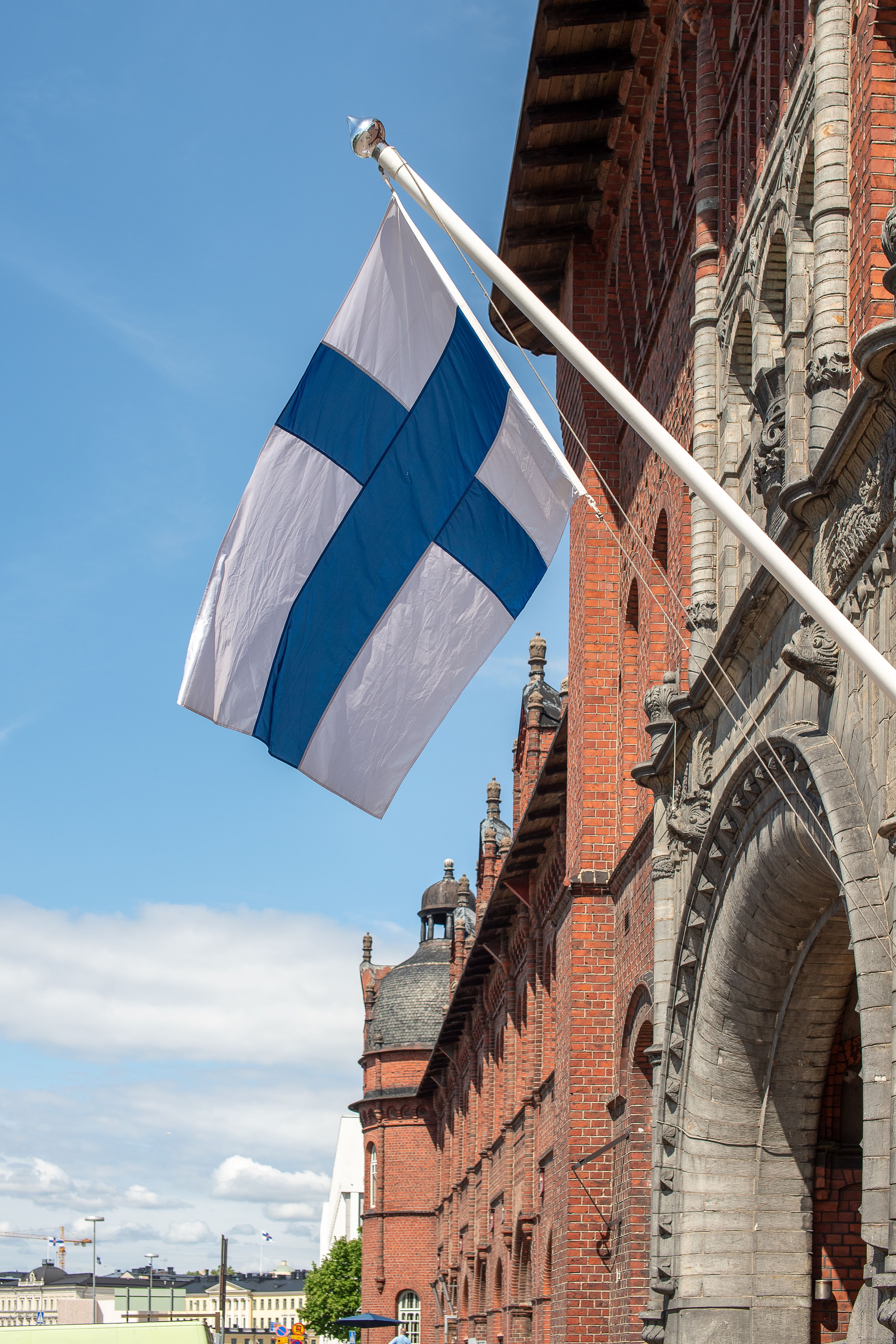A Finnish flag flying beside a historic red-brick building