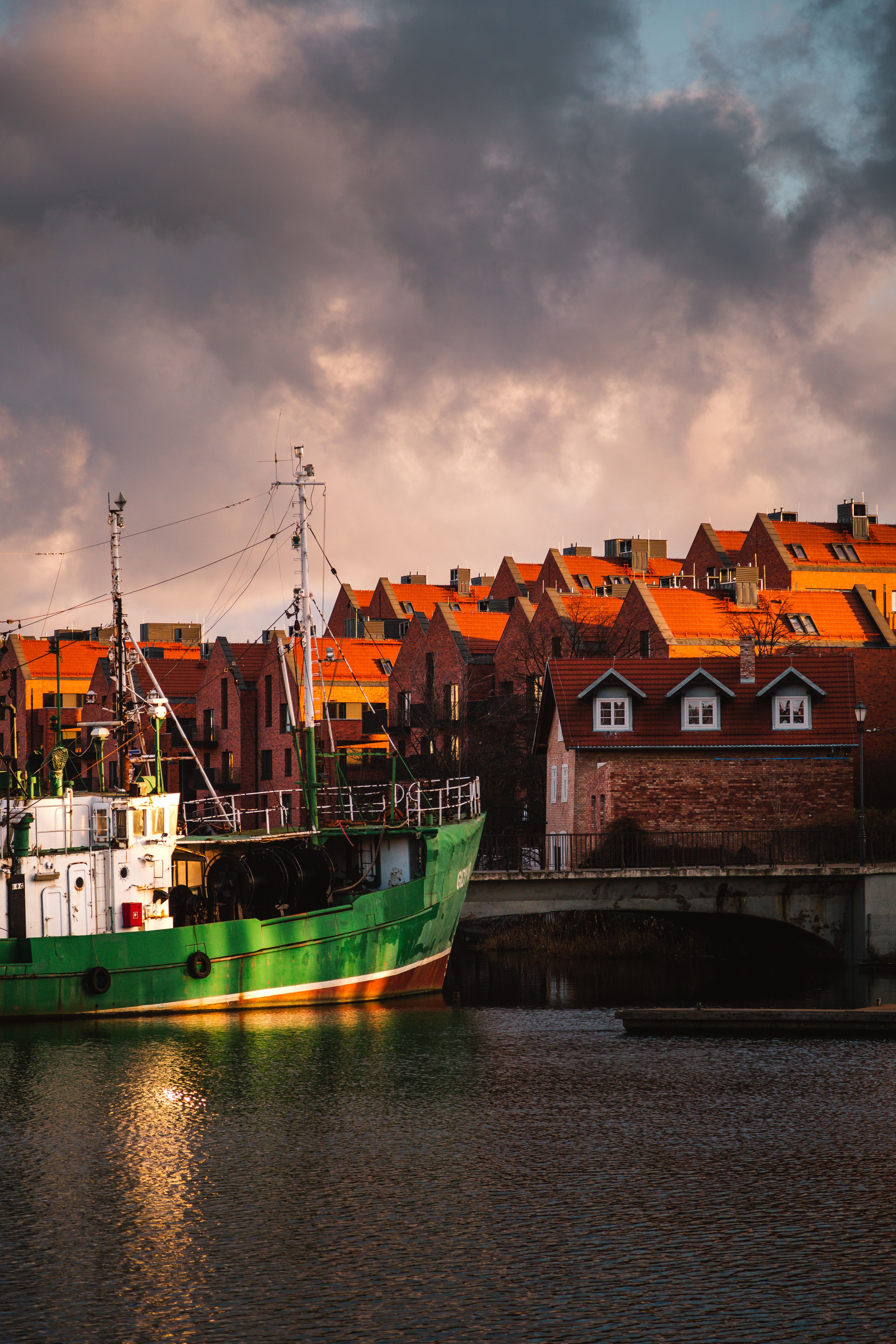 A green fishing vessel moored beside Klaipeda’s brick waterfront buildings