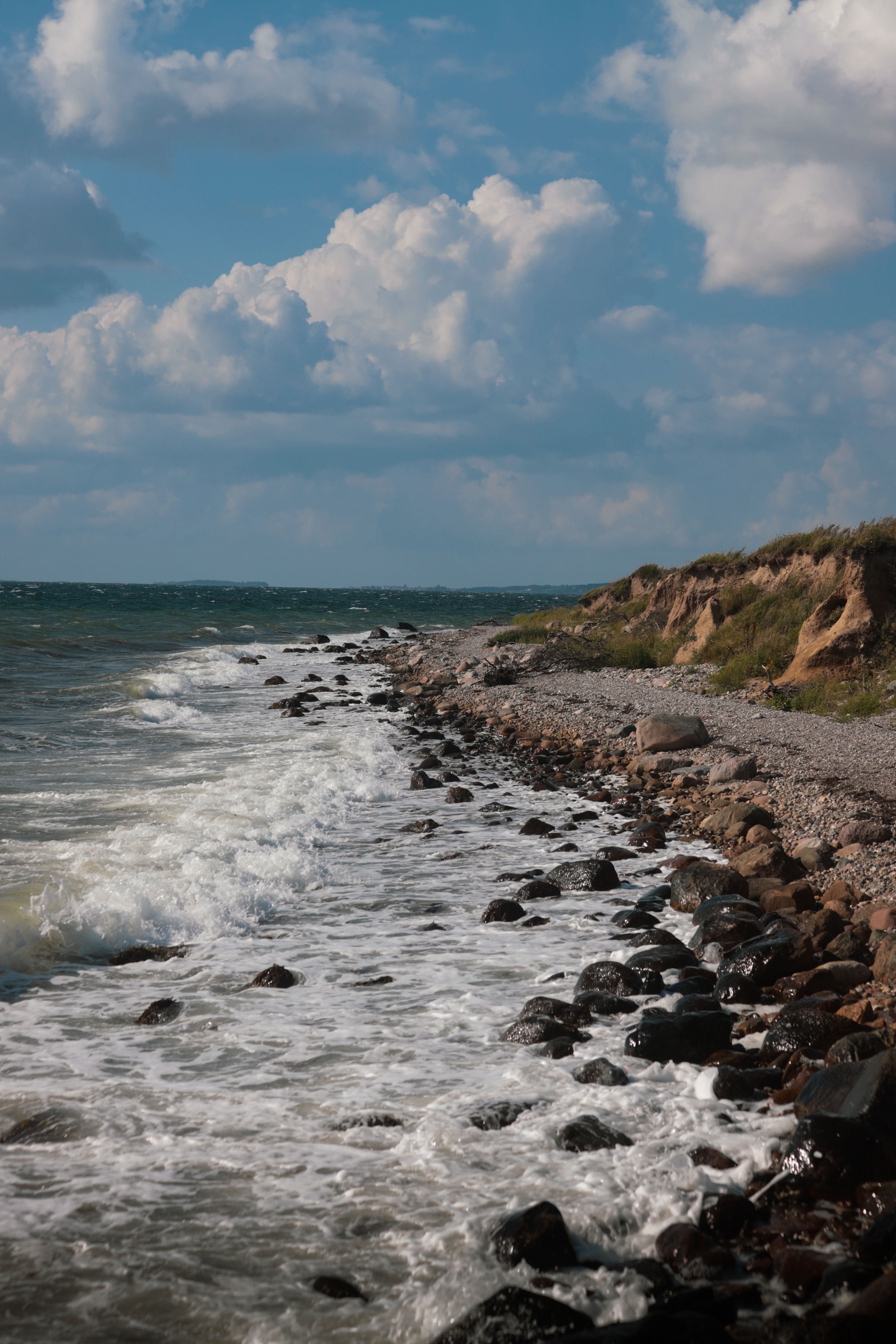 Waves breaking against Bornholm’s rocky coastline and grassy cliffs