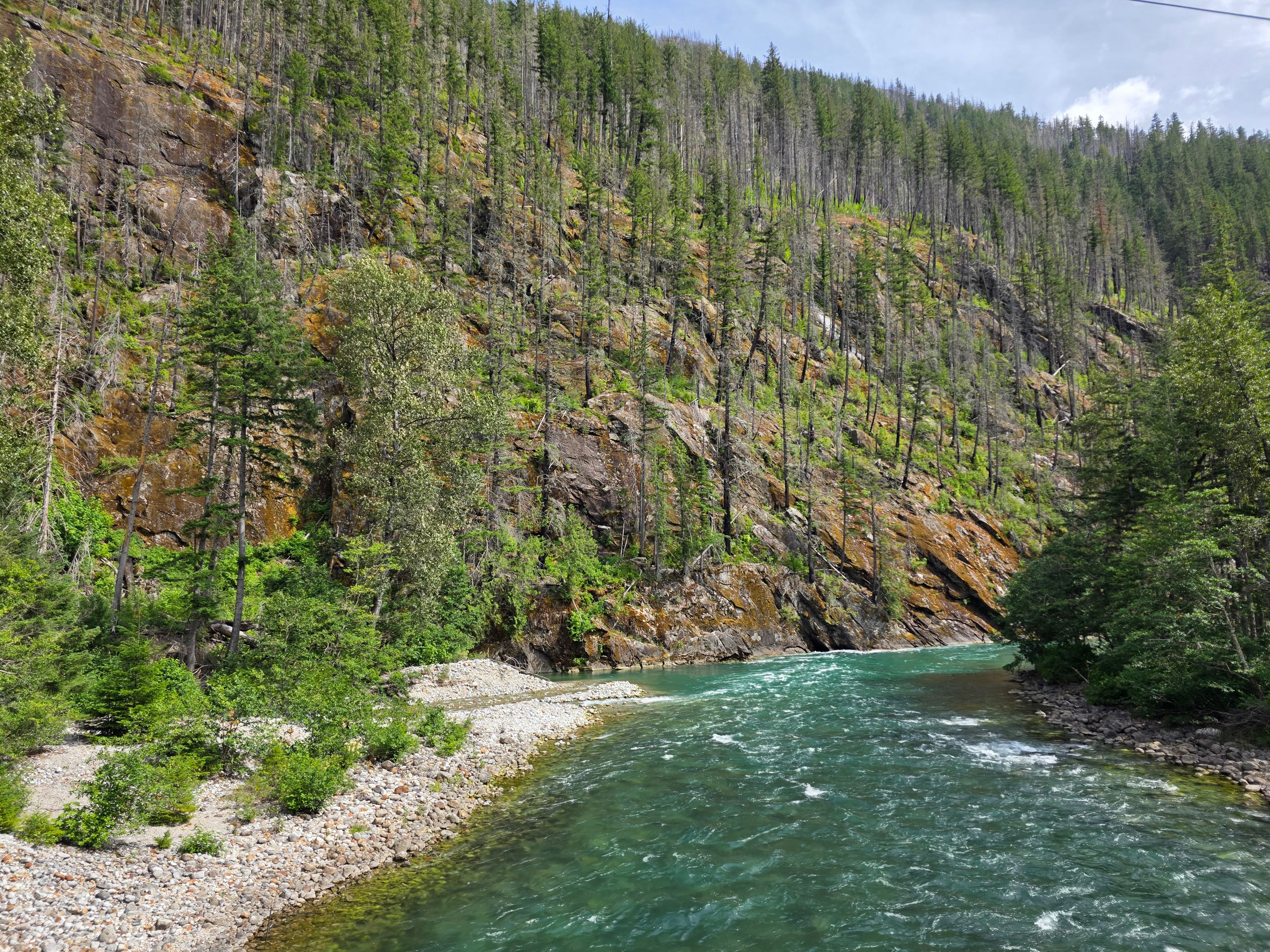 A river flowing beneath forested rocky slopes