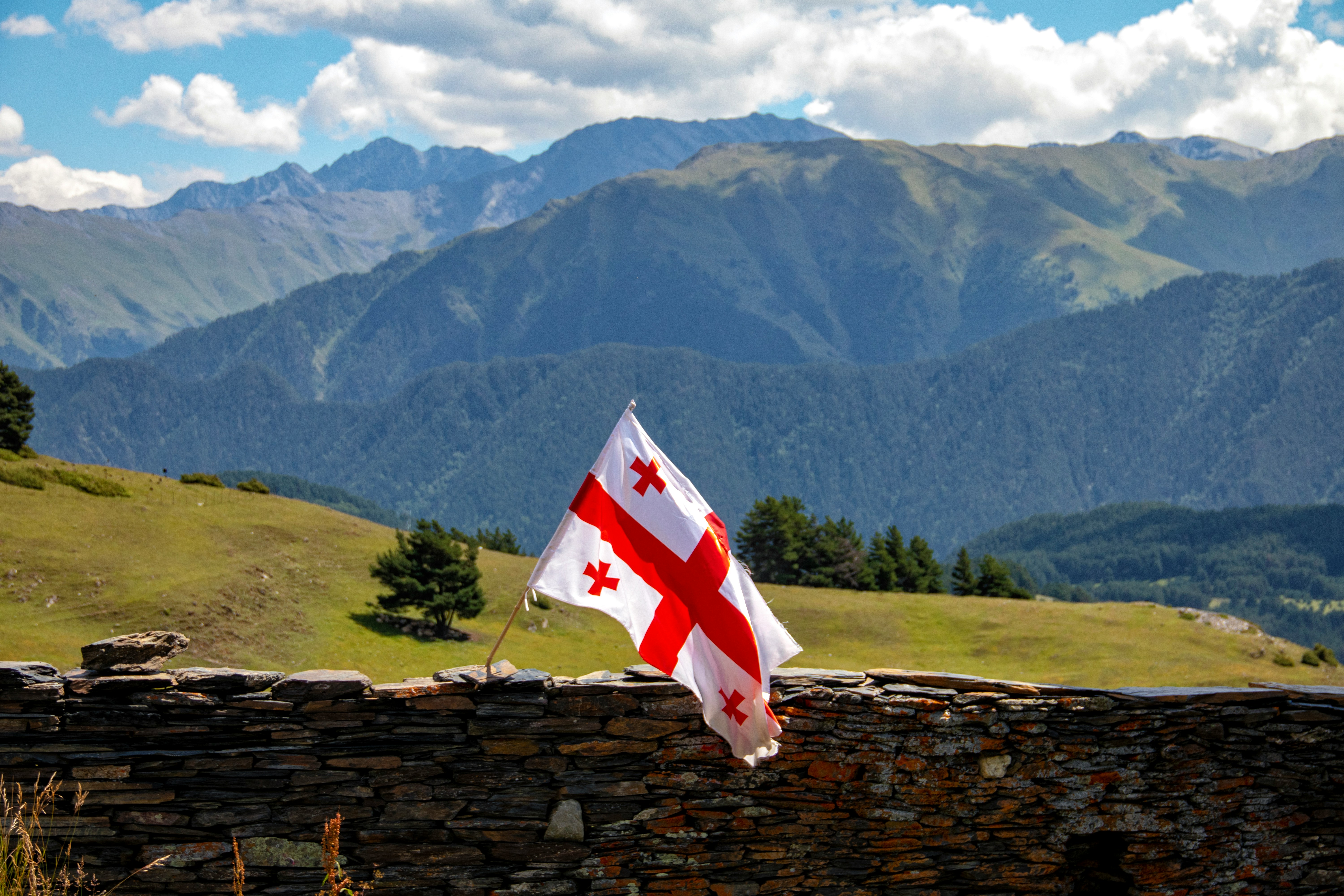 The Georgian flag on a stone wall before the Caucasus mountains
