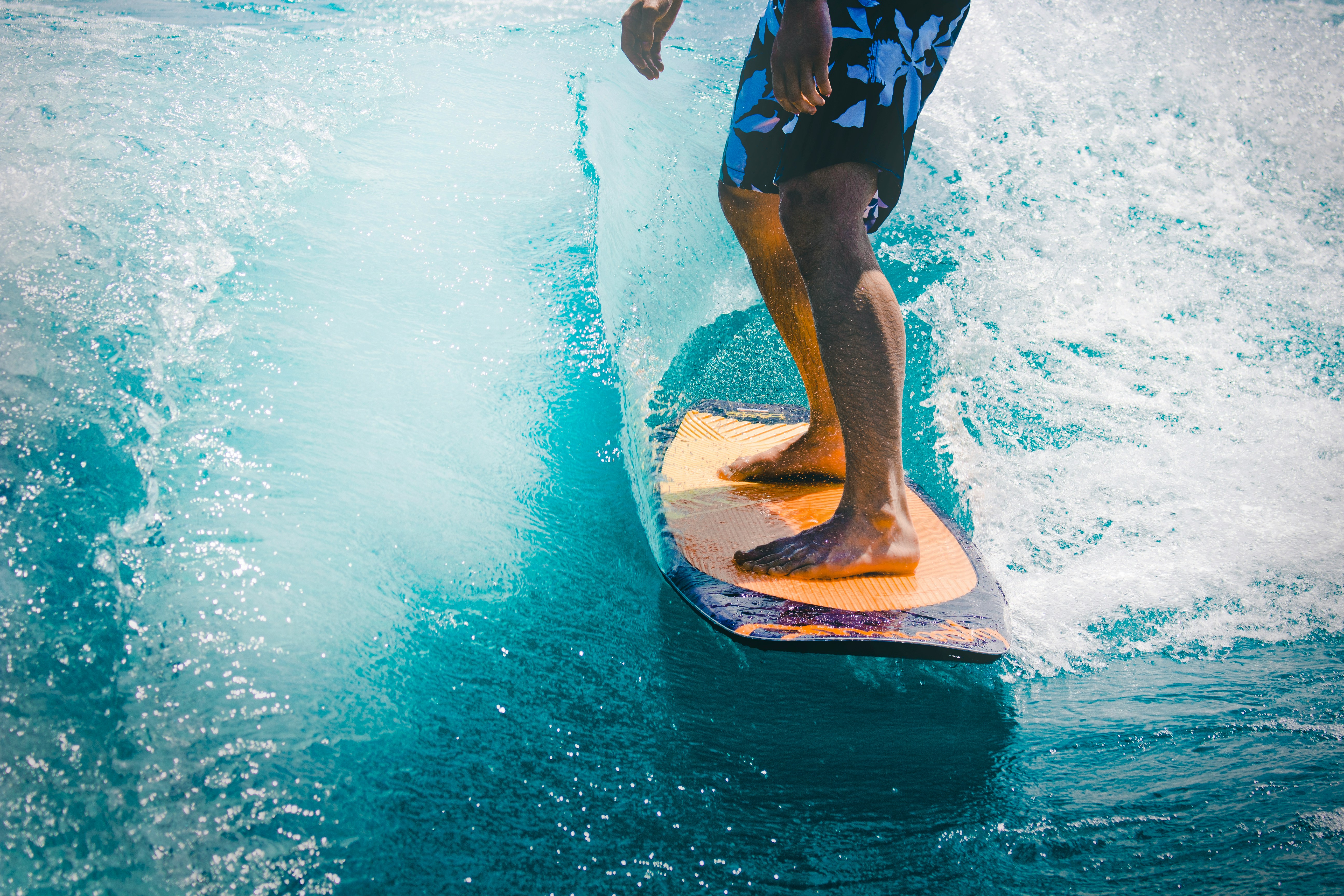 Person riding a board across turquoise water with spray around them