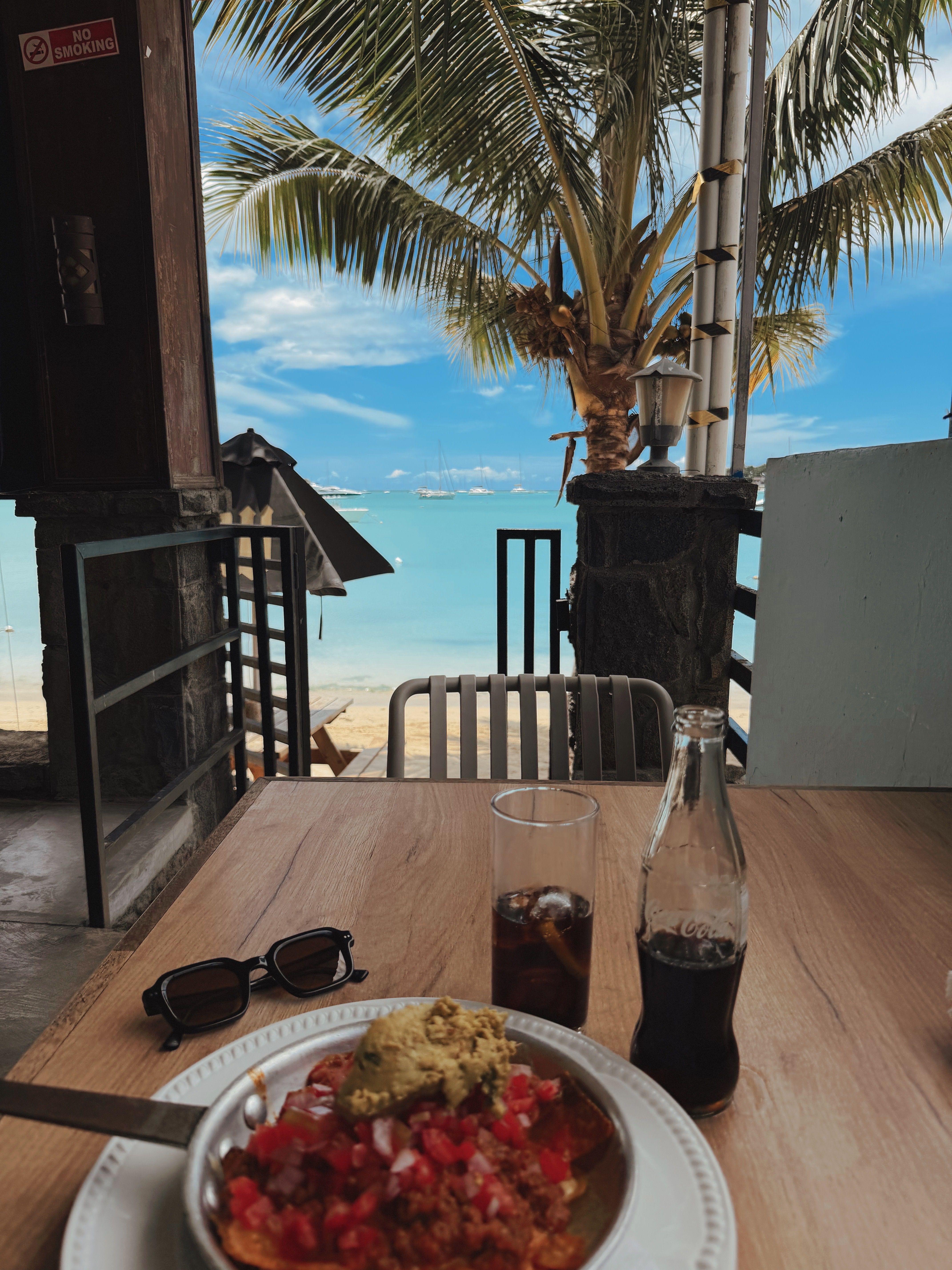 Open-air table beneath palms beside a turquoise lagoon