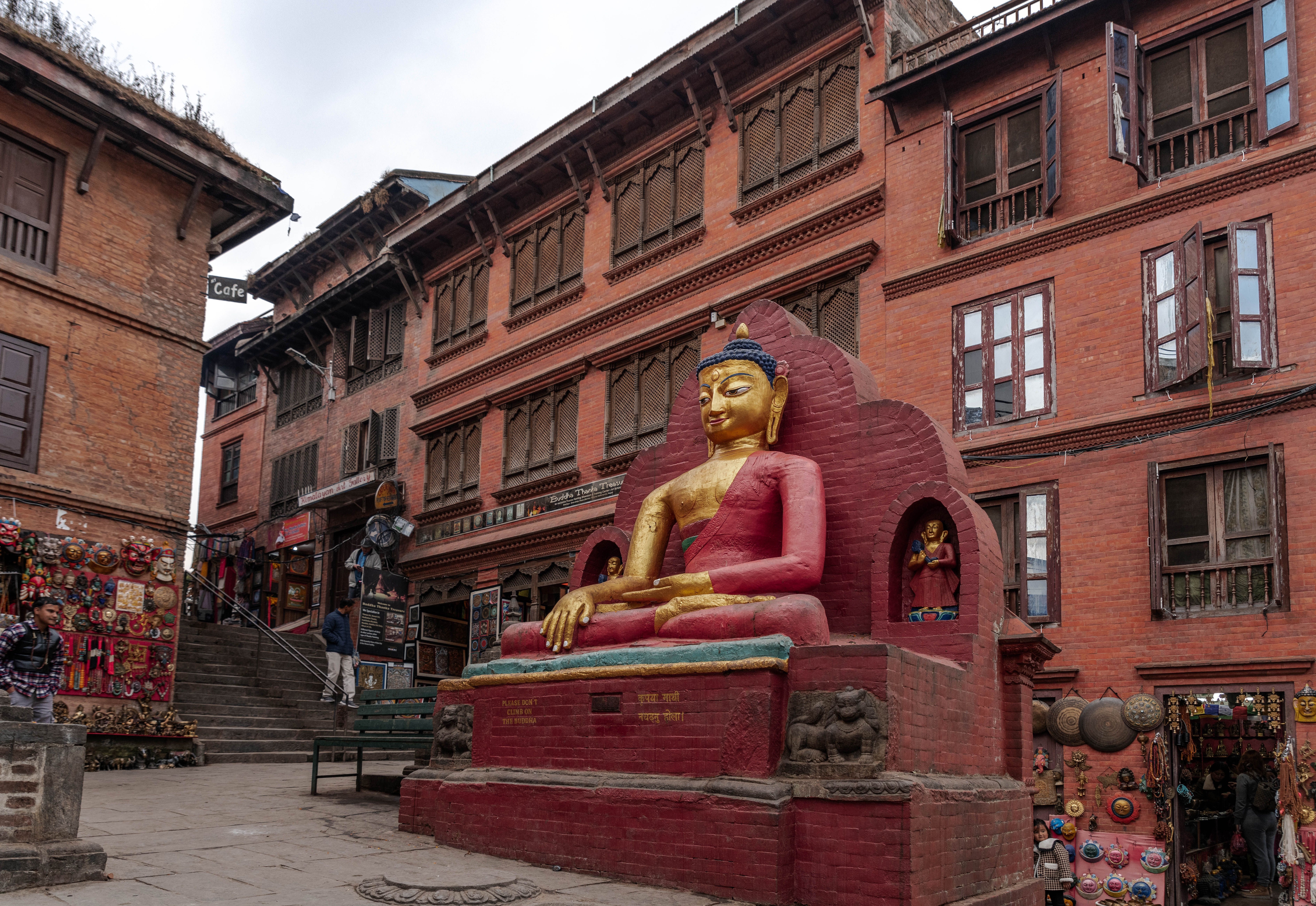 A seated Buddha sculpture in a red-brick courtyard in Kathmandu