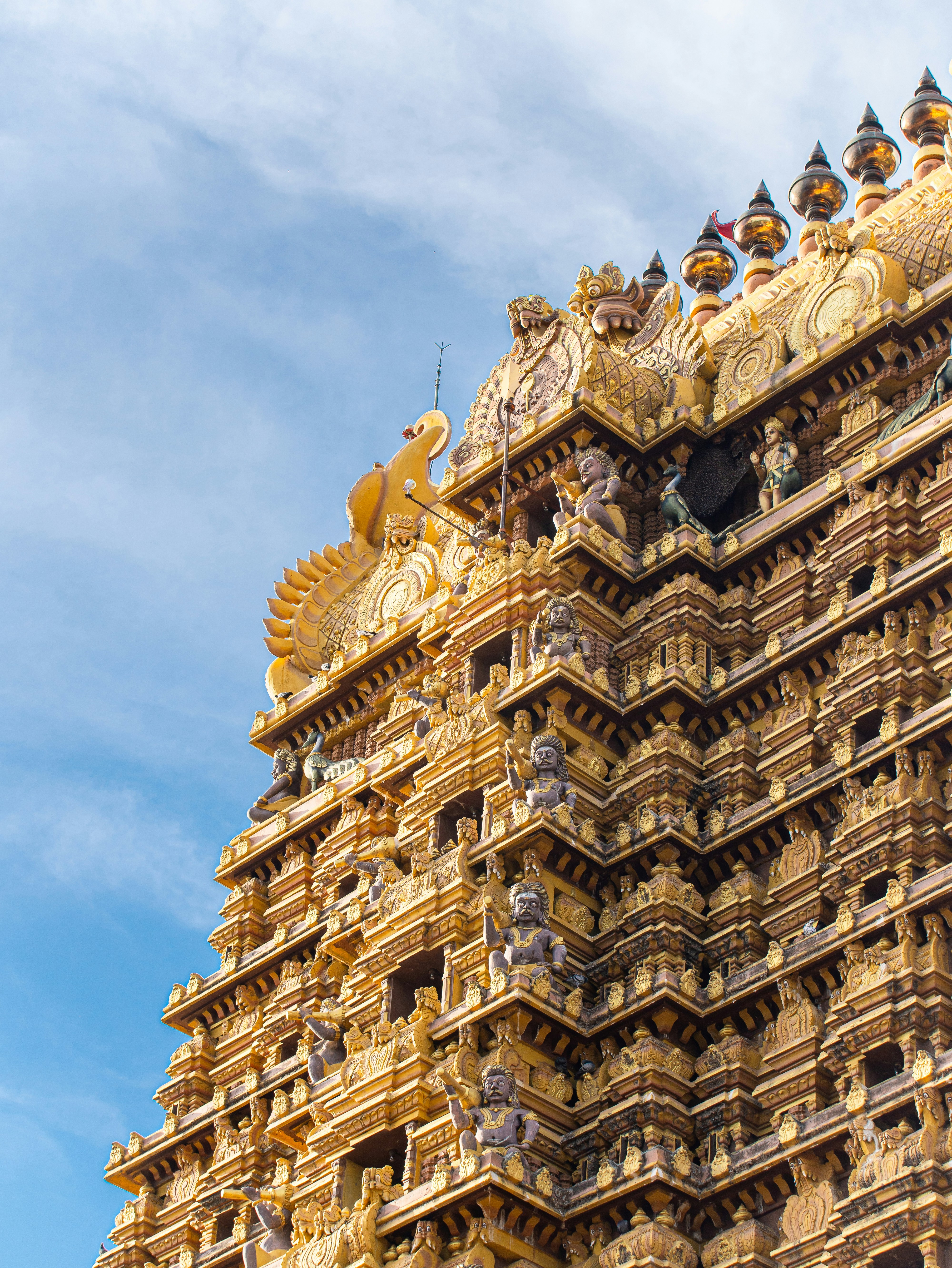 Ornately carved gold-coloured Hindu temple tower against a blue sky