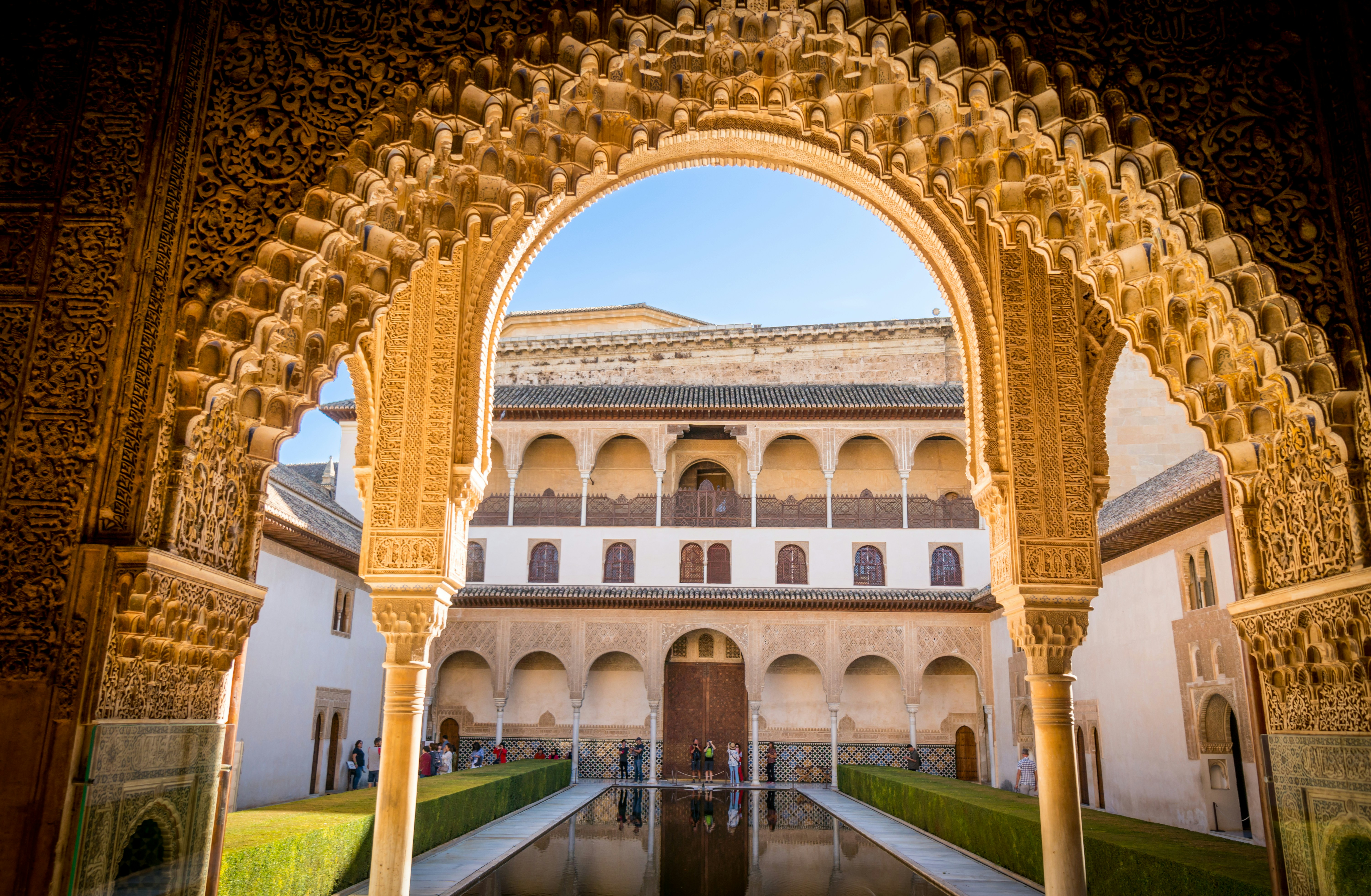 An ornate Moorish arch frames a reflecting pool in the Alhambra.