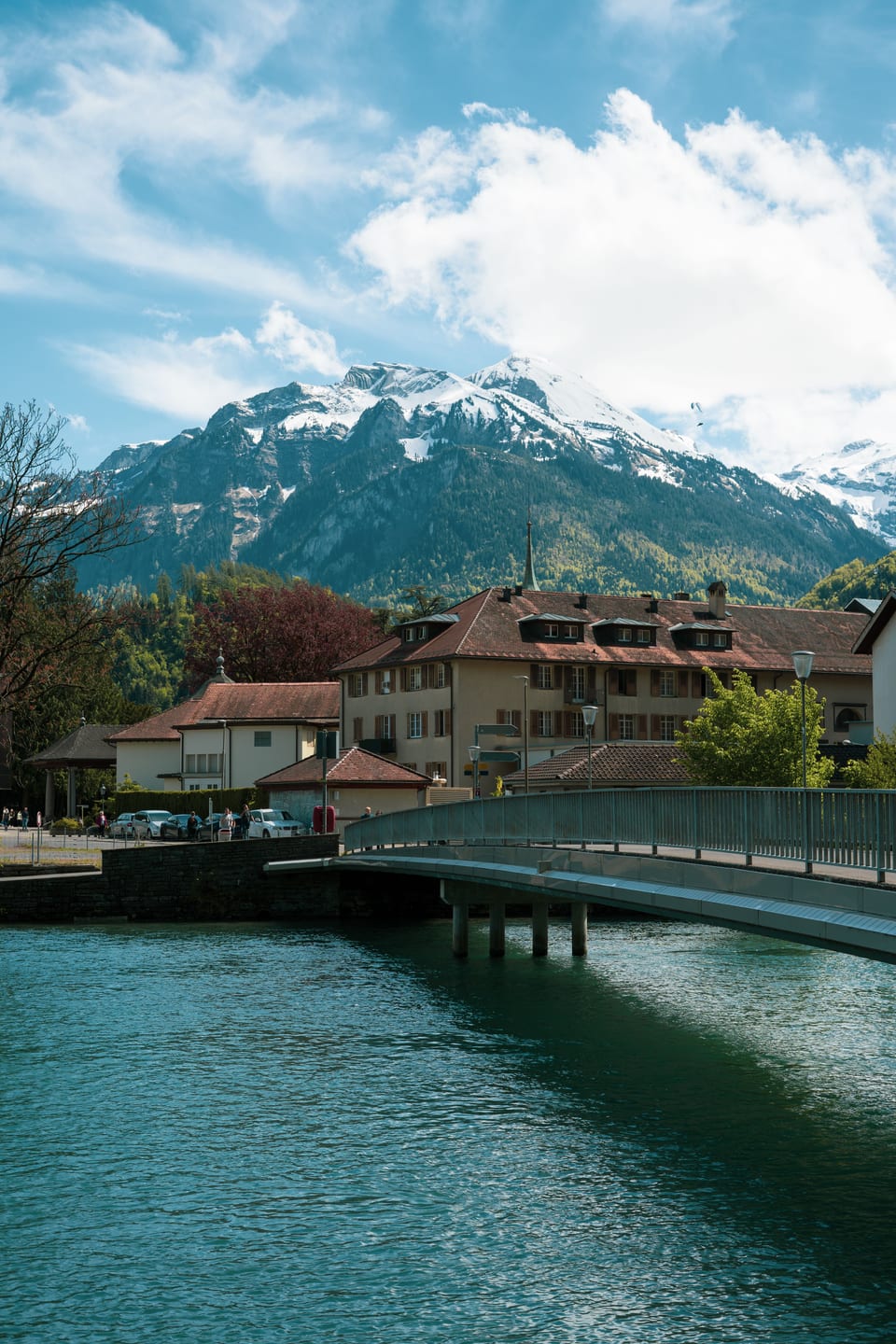 A turquoise alpine river flowing through a Swiss town toward snow-covered mountains