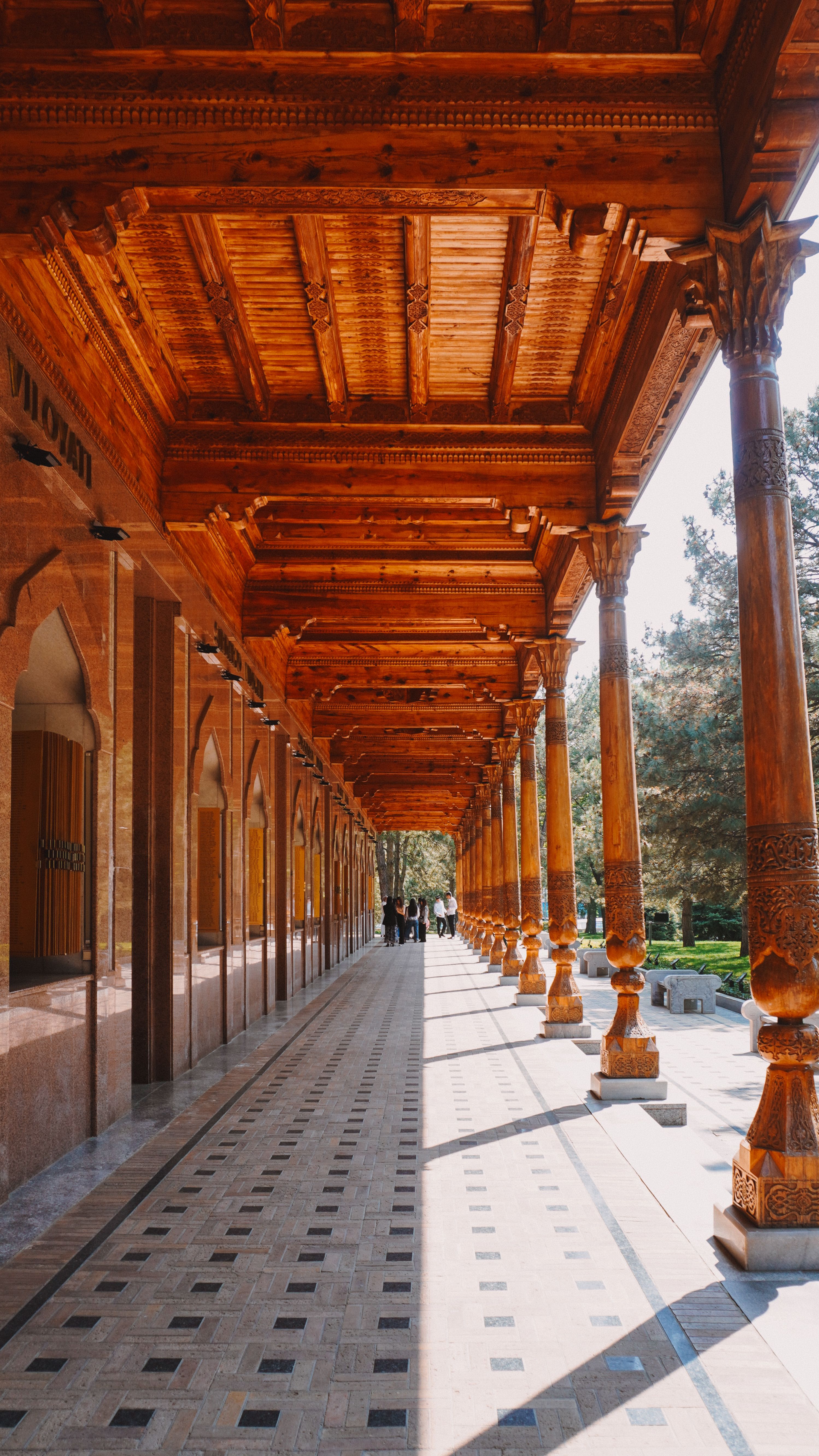 A long carved-timber colonnade and ornate wooden portal at a historic building.