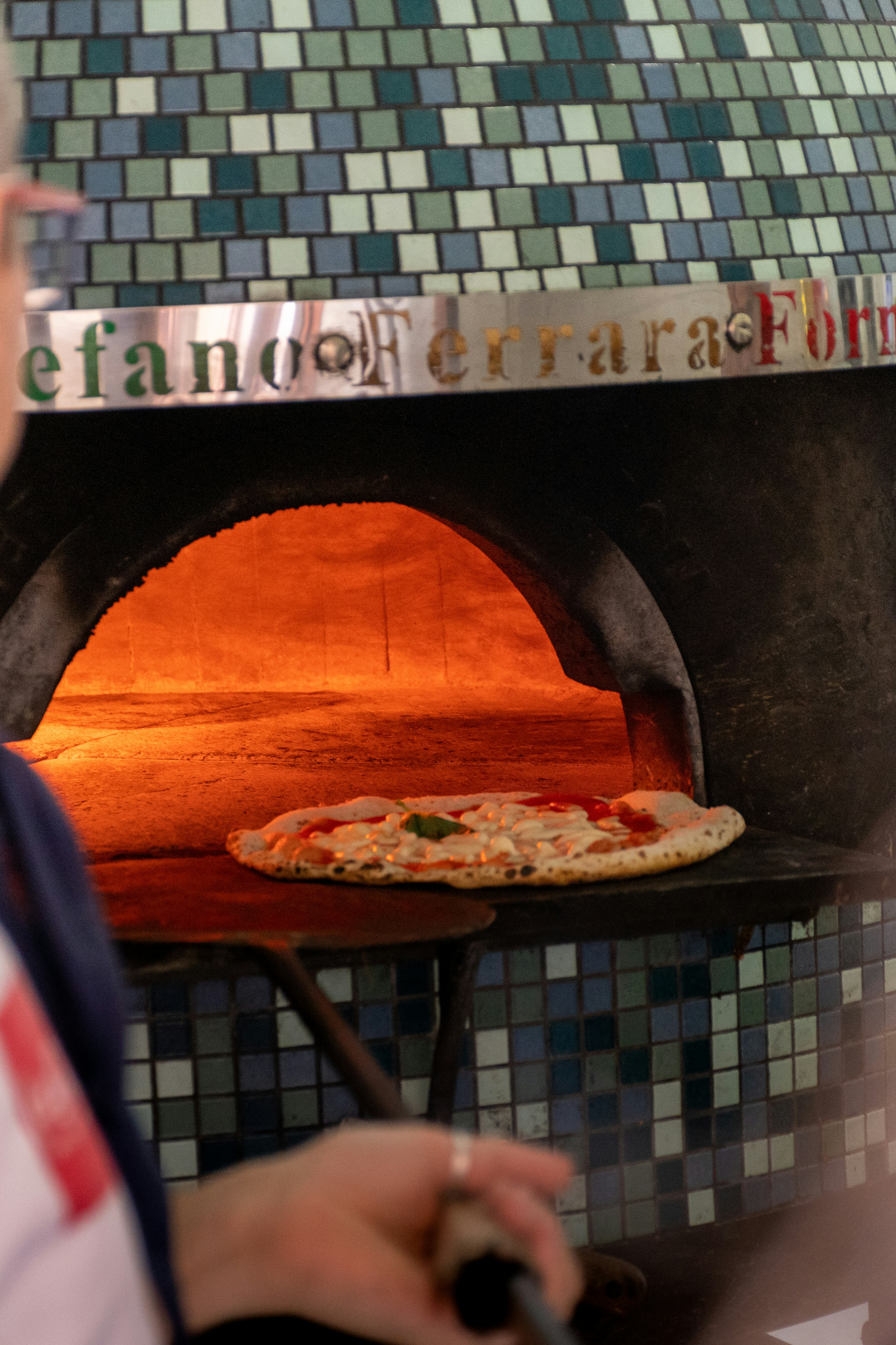 A pizza bakes in a wood-fired oven.