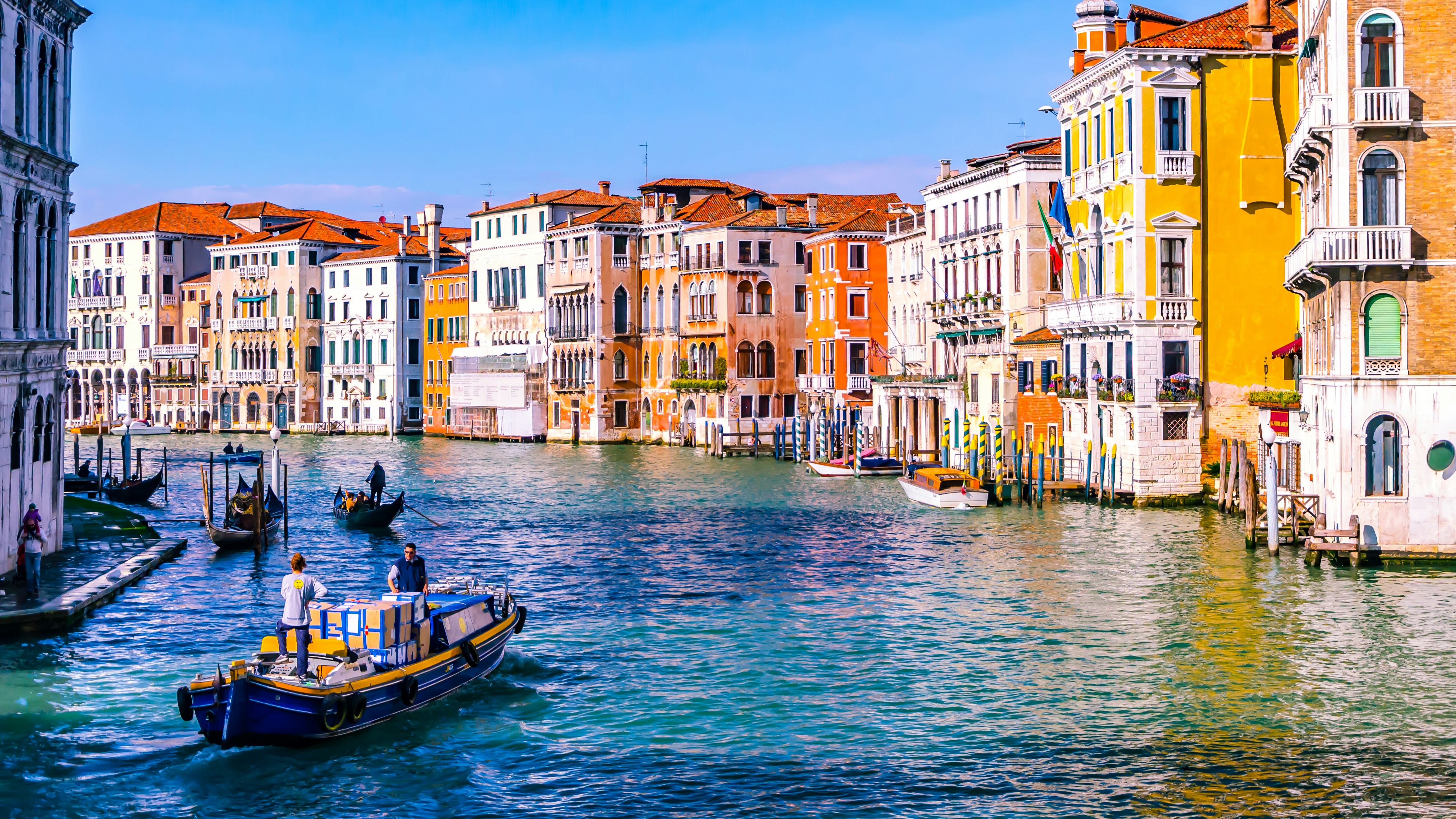 A cargo boat passes historic buildings along a Venice canal.