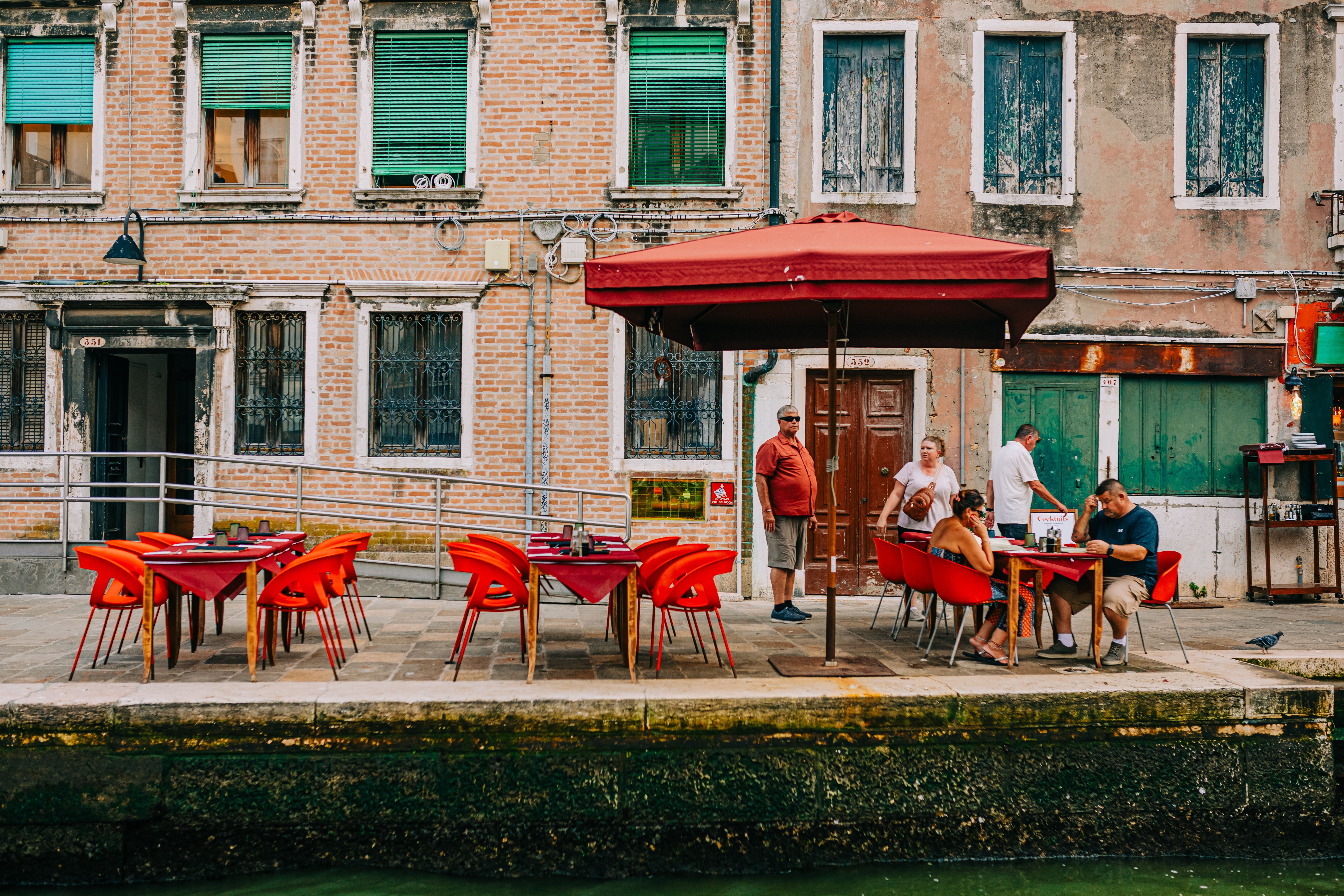 Outdoor café seating beside a narrow canal in Venice.