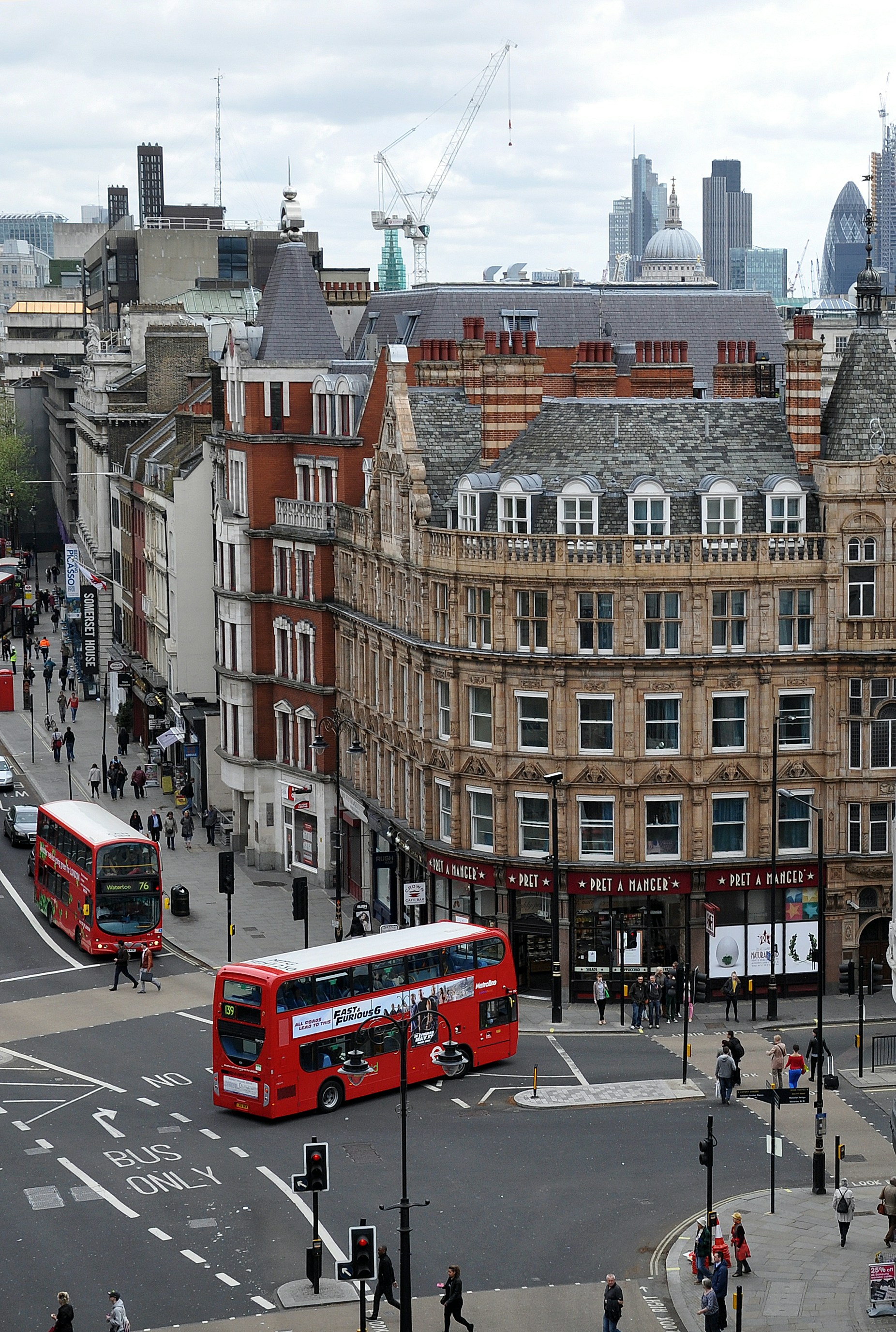 Red double-decker buses pass historic buildings in London