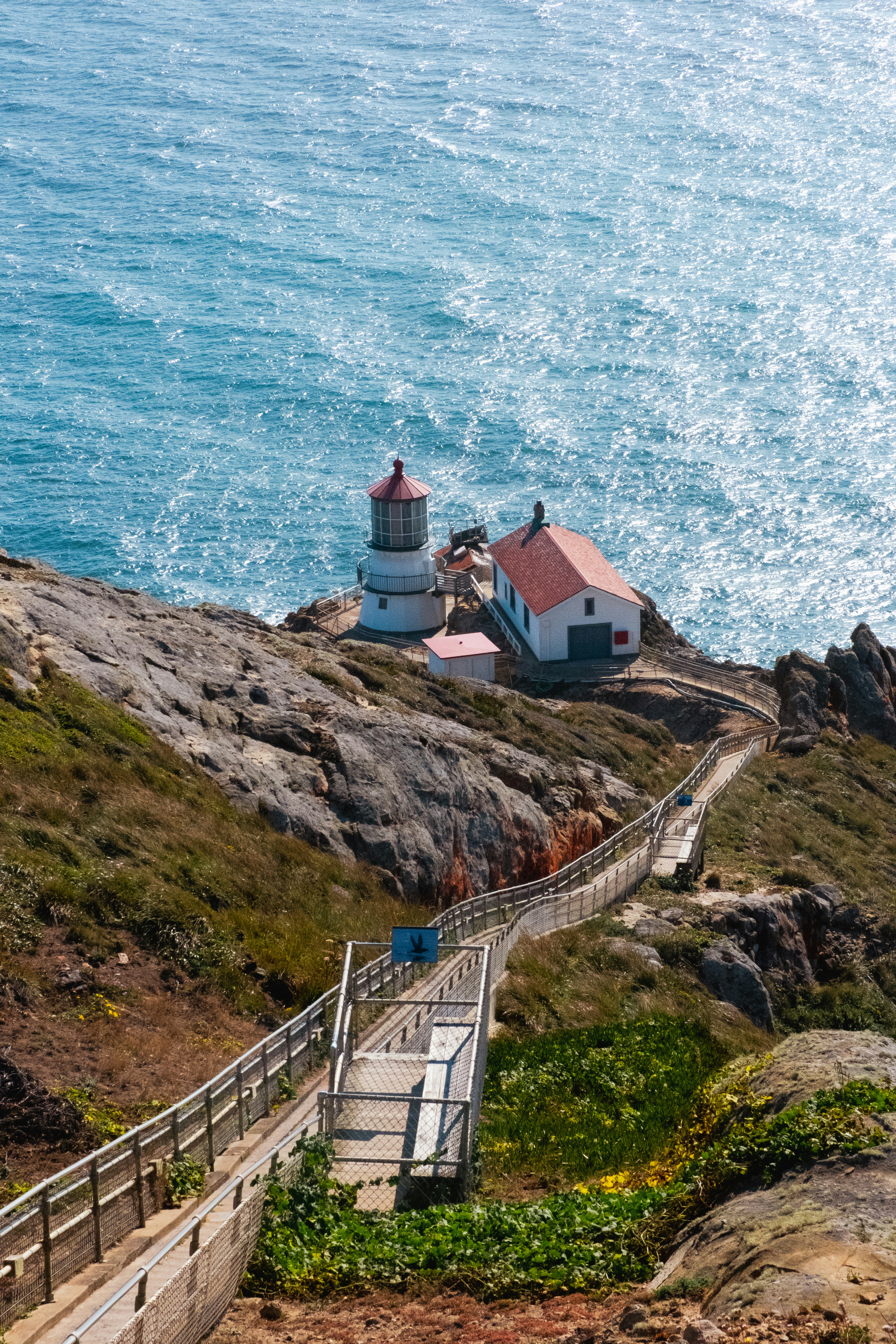A lighthouse on a rocky headland above blue water